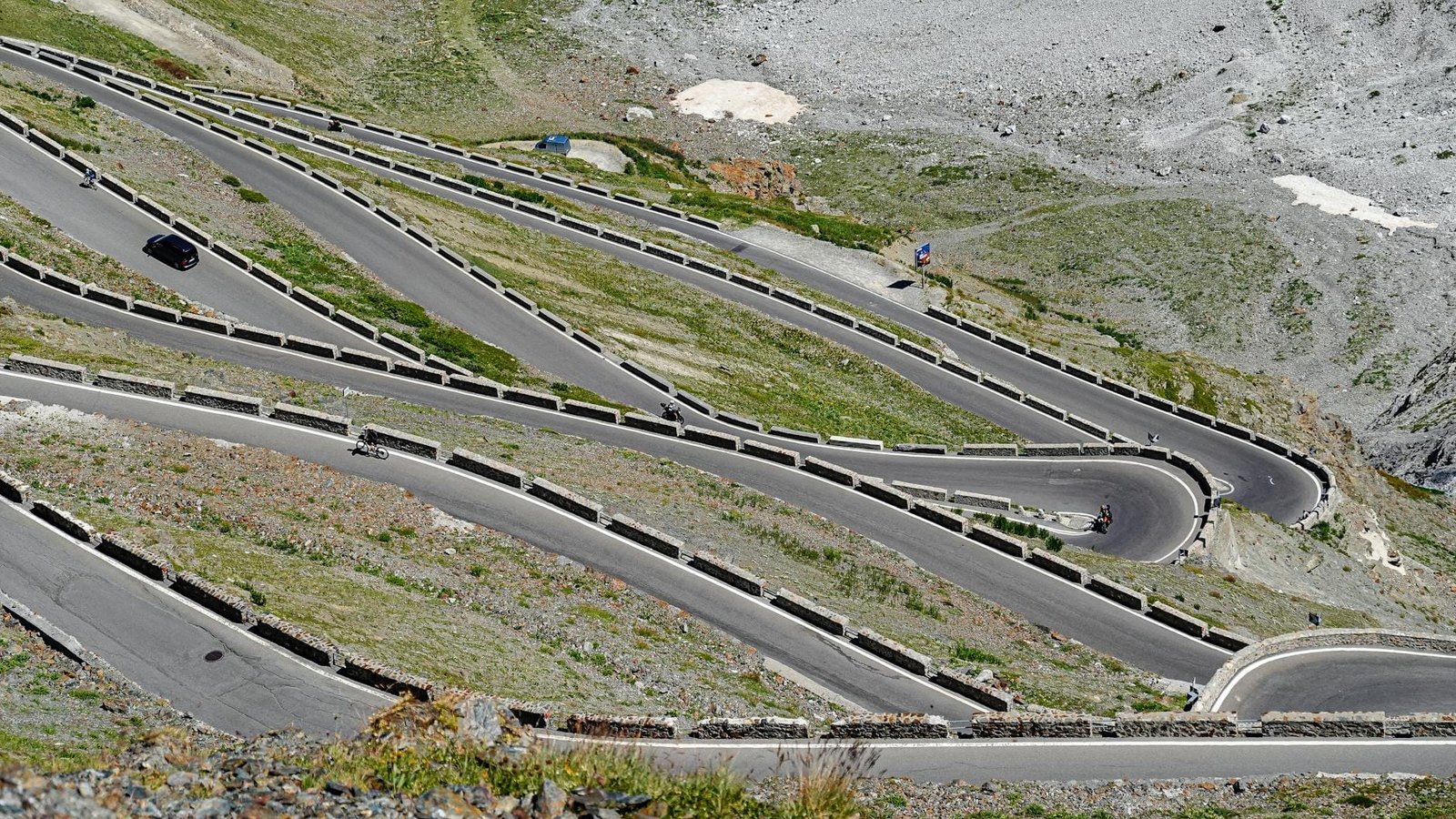 winding mountain road with cyclists and car