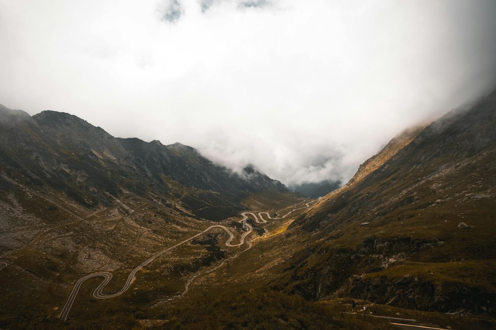 a picturesque view of a winding road in between mountains