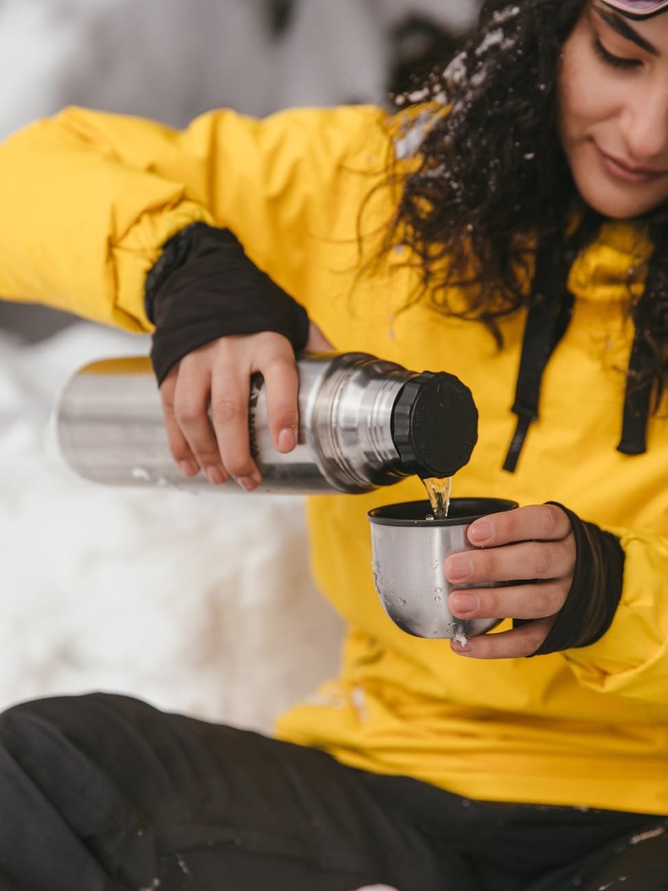 woman pouring water from a stainless water bottle