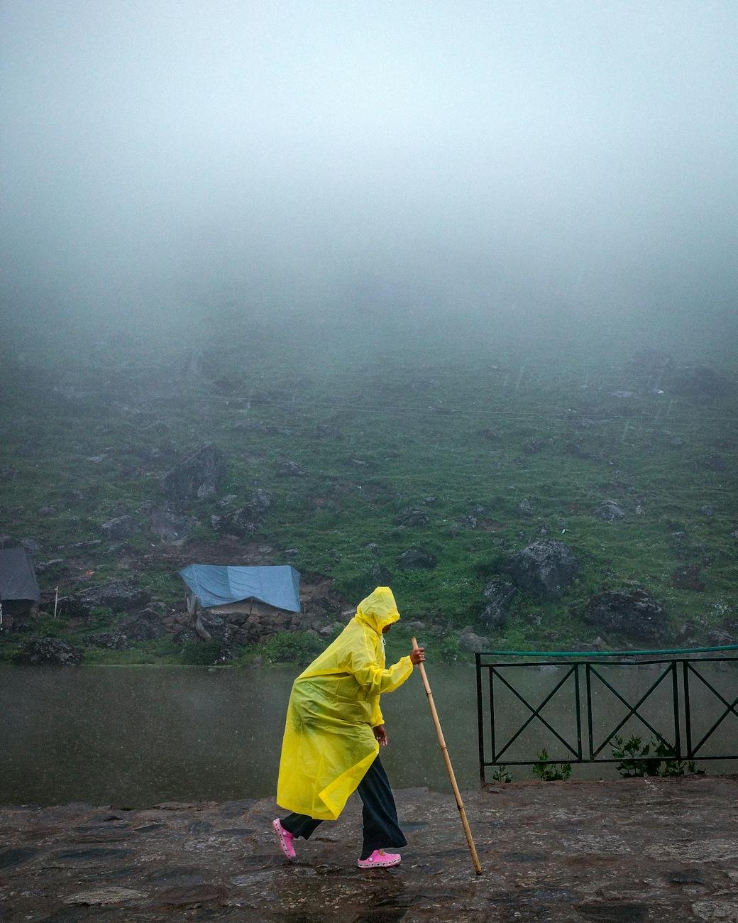 person walking in yellow raincoat on foggy day